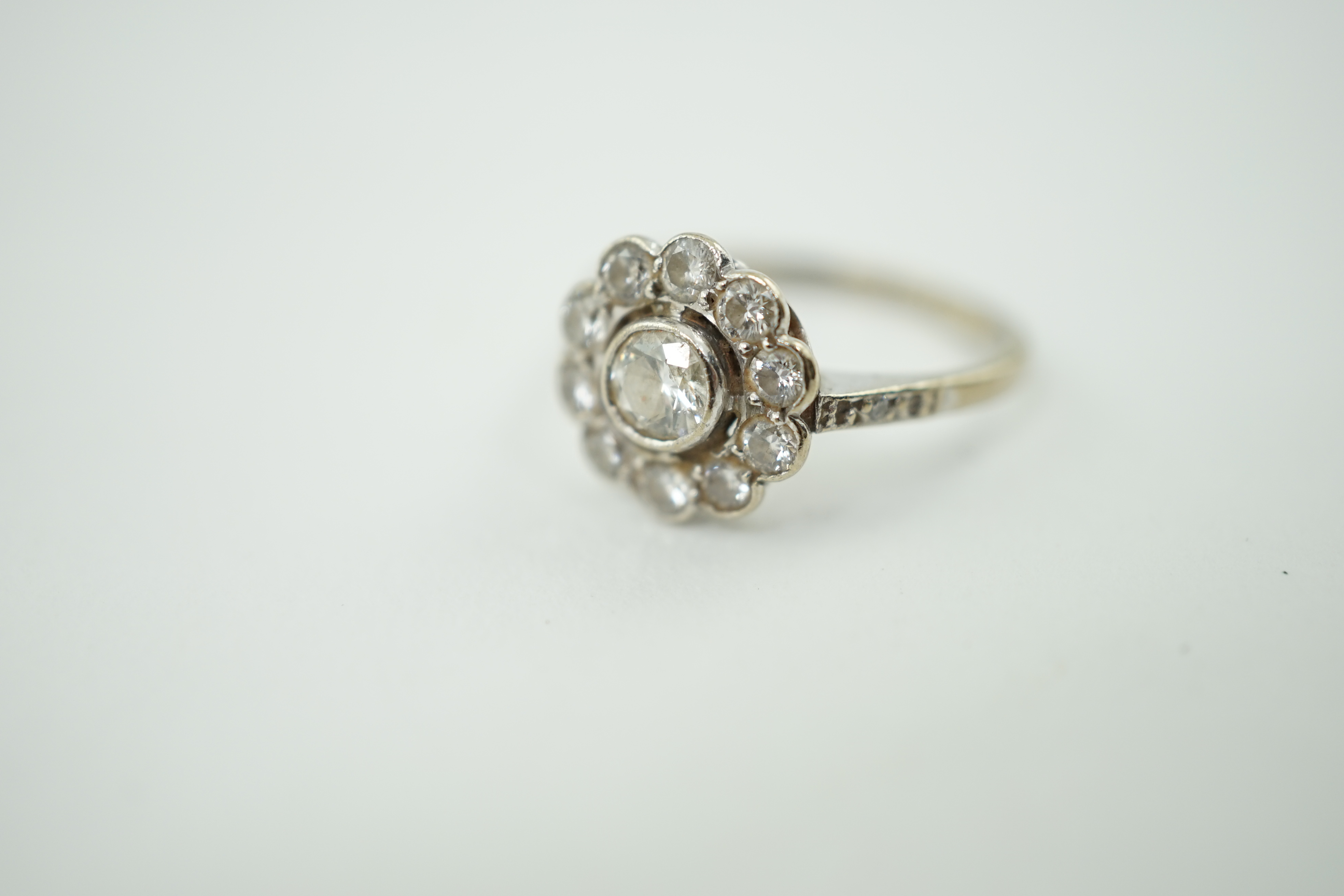 A mid 20th century 18ct white gold and eleven stone diamond set flower head cluster ring